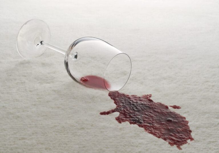 An overturned wine glass with red wine spilled on a white carpet, now a job for Sammamish Carpet Cleaning.